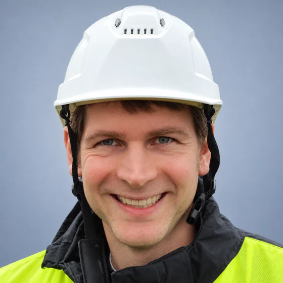 Porträt von Philipp von der Born mit weißem Schutzhelm und Warnjacke